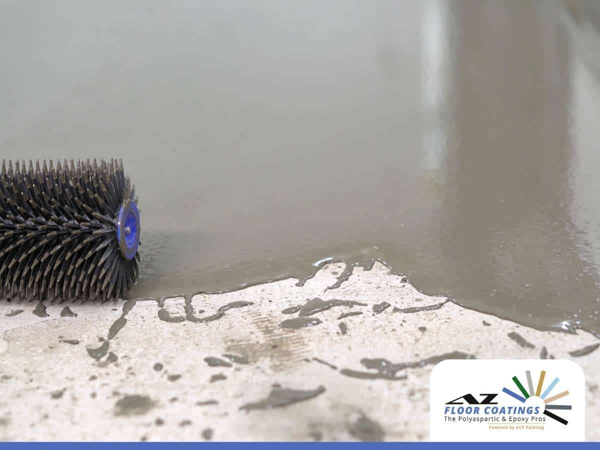 A spiked roller applies epoxy coating to a concrete floor